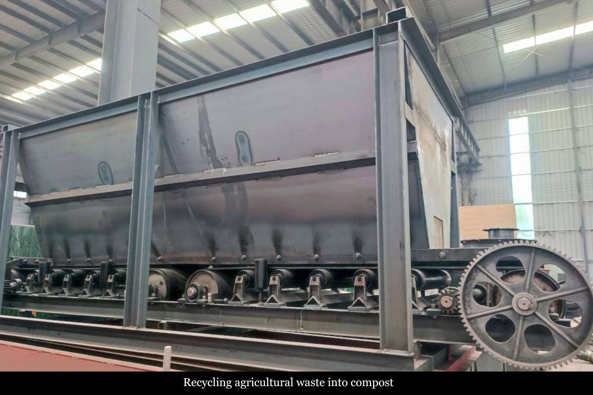 Large industrial machine inside a warehouse, featuring gears and a conveyor, used for recycling agricultural waste into compost.